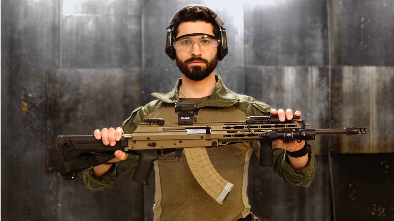 Instruktor mit Gehörschutz und Schutzbrille hält ein Gewehr